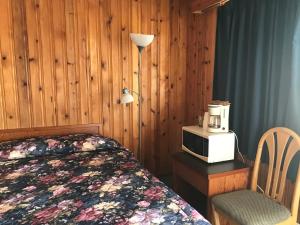 a bedroom with a bed and a microwave and a chair at Glacier View Inn in Haines Junction
