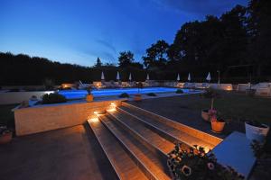 una piscina por la noche con un banco y luces en Apartments Tena, en Poreč