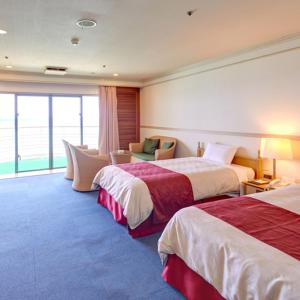 una habitación de hotel con 2 camas y una silla en Resort Hotel Bel Paraiso, en Nakijin
