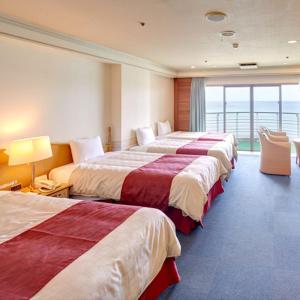 Habitación de hotel con 4 camas y balcón en Resort Hotel Bel Paraiso, en Nakijin