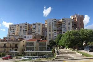 un edificio de apartamentos alto con coches aparcados en un aparcamiento en Apartment Veseli, en Split