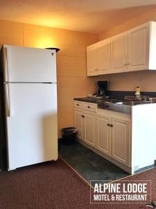 a kitchen with a white refrigerator and white cabinets at Alpine Lodge Motel & Restaurant in Grande Cache