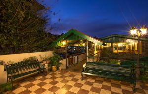 un par de bancos sentados en un patio por la noche en Pine Borough Inn en Kodaikānāl