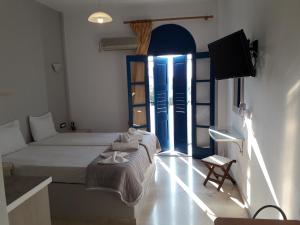 a bedroom with two beds and a tv in a room at Katefiani Villas in Perissa