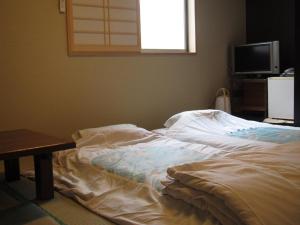 an unmade bed in a room with a television at Ryokan Fuji in Tokyo