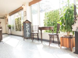 um quarto com duas cadeiras, uma mesa e janelas em SSIP Boutique Dhevej Bangkok em Banguecoque