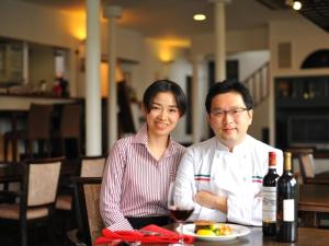 a man and woman sitting at a table with a glass of wine at Petit Resort Hotel Alcyon in Ito