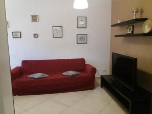 a living room with a red couch and a tv at Le cisterne Holiday Home in Manfredonia