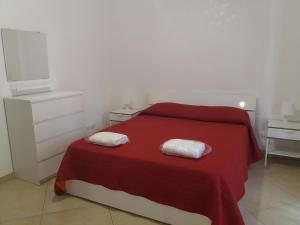 a bedroom with a red bed with two towels on it at Le cisterne Holiday Home in Manfredonia