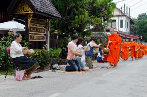 een groep monniken in oranje gewaden die door een straat lopen bij Villa Chitdara in Luang Prabang