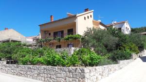 une maison sur une colline avec un mur en pierre dans l'établissement Apartments Dragan, à Stari Grad