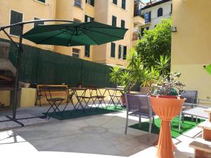 eine Terrasse mit einem grünen Sonnenschirm, Stühlen und Tischen in der Unterkunft Clodio Rooms in Rom