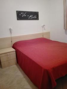 um quarto com uma cama vermelha e uma placa na parede em Les jardins de la mer marine de bravone - 2 chambres à lit plus sofa avec piscine à coté mer em Linguizzetta