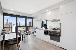 a kitchen with white cabinets and a dining room with a view at Platinum City Serviced Apartments in Melbourne