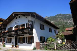 ein weißes Gebäude mit einem Balkon und einem Berg in der Unterkunft Gästehaus Nicole in Garmisch-Partenkirchen