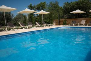 una piscina con sillas y sombrillas en Gea Villas, en Ligia