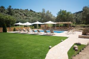 une pelouse avec des chaises et des parasols ainsi qu'une piscine dans l'établissement Gea Villas, à Lygia