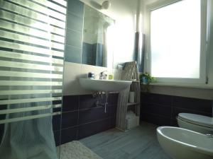 ein Badezimmer mit einem Waschbecken, einem WC und einem Spiegel in der Unterkunft One More Night in Fregene