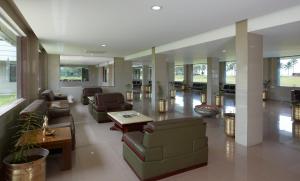 een grote lobby met banken, tafels en ramen bij RNS Golf Resort & Nature Cure Centre in Māvalli