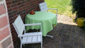 2 chaises et une table avec un tissu de table vert dans l'établissement Ferienwohnung Ahausen, à Ahausen