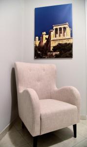 a white chair in a room with a painting on the wall at Daphne's Apartment in Athens