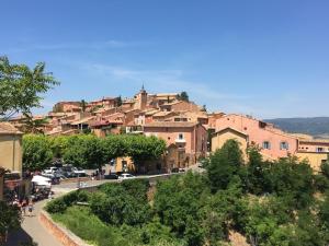 une ville sur une colline avec des voitures garées dans une rue dans l'établissement Maison au pied des ocres, à Roussillon