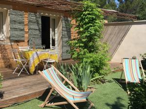 um pátio com uma mesa e cadeiras num deque em Maison au pied des ocres em Roussillon