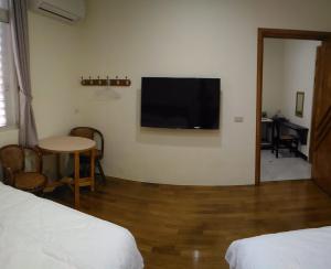 a bedroom with a flat screen tv on the wall at Wooden Man Homestay in Taitung City