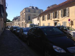 a row of cars parked on the side of a street at Le Petit Pavillon de Versailles in Versailles