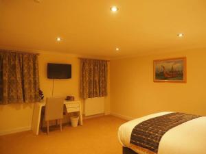 a bedroom with a bed and a desk and a television at Thai Season in York