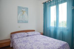 sypialnia z łóżkiem z niebieskimi zasłonami i oknem w obiekcie Latmo Apartment Zadar w mieście Zadar