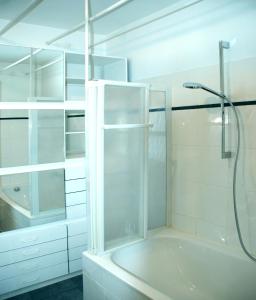 ein weißes Bad mit einer Dusche und einer Badewanne in der Unterkunft Artist Residence Schwabing in München