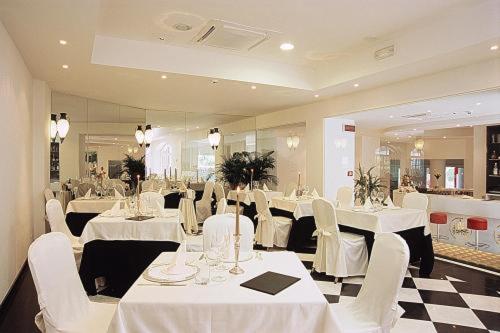 un comedor con mesas blancas y sillas blancas en M Glamour Hotel, en Gabicce Mare