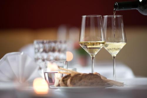 two glasses of white wine next to a plate of food at Ambassador Parkhotel in Munich