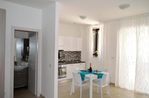 cocina blanca con mesa y sillas blancas en Largo Cannizzaro Apartments, en Mazzeo