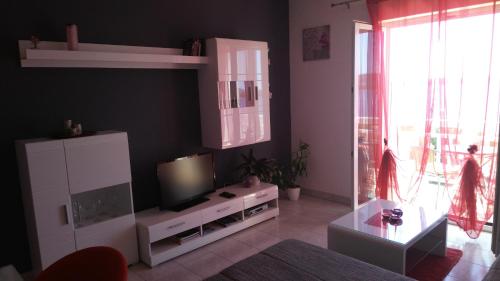 a living room with a flat screen tv and a table at Apartments Zunic in Trogir
