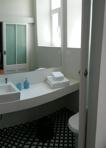 a bathroom with a sink and a toilet and a mirror at Alcaçaria do Bairro in Setúbal