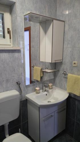 a bathroom with a sink and a toilet and a mirror at Apartments Zunic in Trogir