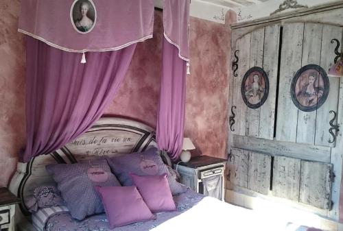 ルシヨンにあるMaisonnette La médievale du Lubéronのベッドルーム1室(紫色のカーテン、紫色の枕付きのベッド1台付)