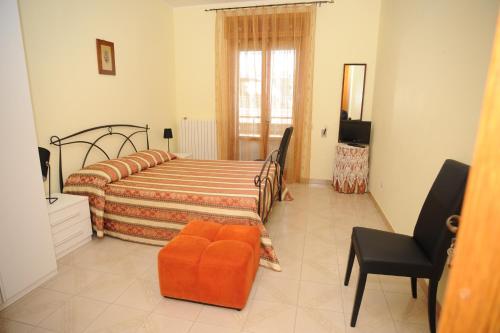 a bedroom with a bed with an orange chair at B&B Vie En Rose in Porto Cesareo