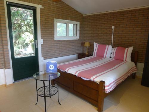 1 dormitorio con 1 cama con mesa y ventana en B&B De Kleine Wijngaard, en Roggel