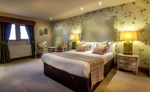 The Huntsman Inn في هولمفيرث: غرفة نوم مع سرير كبير مع زهور على الحائط
