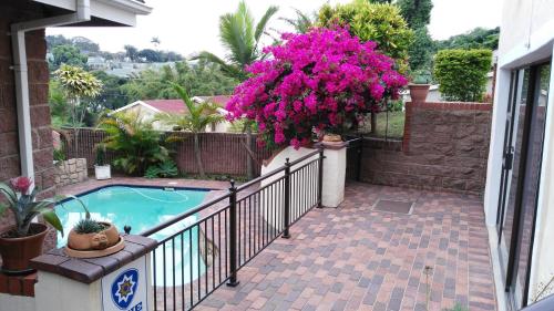 a balcony with a swimming pool and pink flowers at Lily's Cottage in Durban