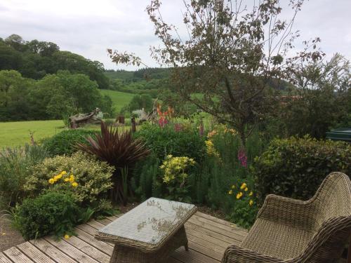 a garden with a wooden deck with two chairs and flowers at Sid Valley Country House Hotel in Sidmouth