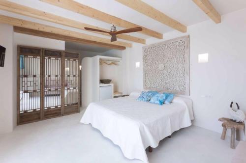 a white bedroom with a bed with blue pillows at Boho Suites Denia in Denia
