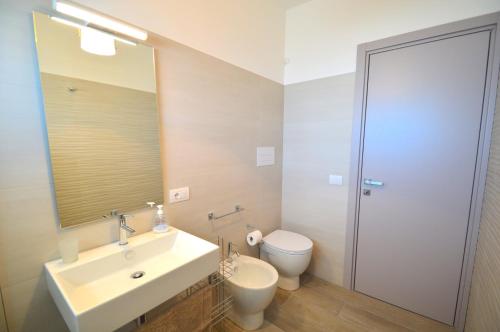 a bathroom with a sink and a toilet and a mirror at Yachting Apartment in Marzamemi