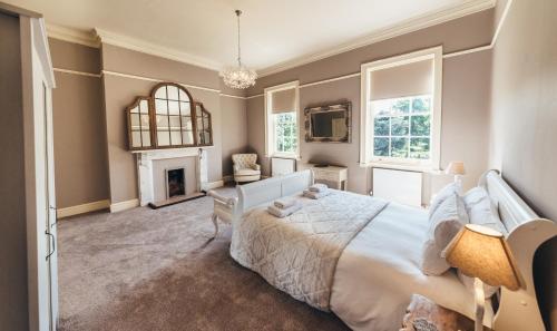 a bedroom with a large white bed and a fireplace at Birchover Bridgford Hall in Nottingham
