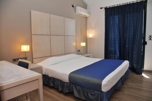 Pokój hotelowy z dużym łóżkiem i biurkiem w obiekcie Plaza Hotel w mieście Lutraki