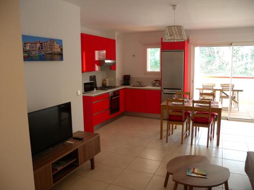 a kitchen and dining room with red cabinets and a table at HENDAYE- T2 3*-Wifi-350m plage-terrasse-garage in Hendaye