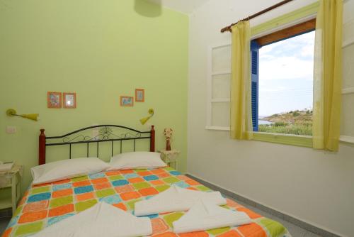 a bedroom with a bed and a window at Dora's Studios & Apartments in Megas Yialos-Nites